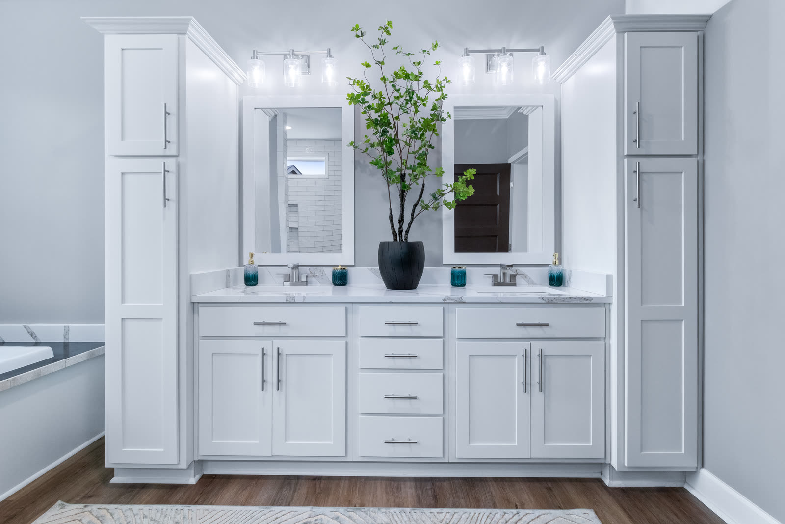 Double vanity between tall white linen cabinets