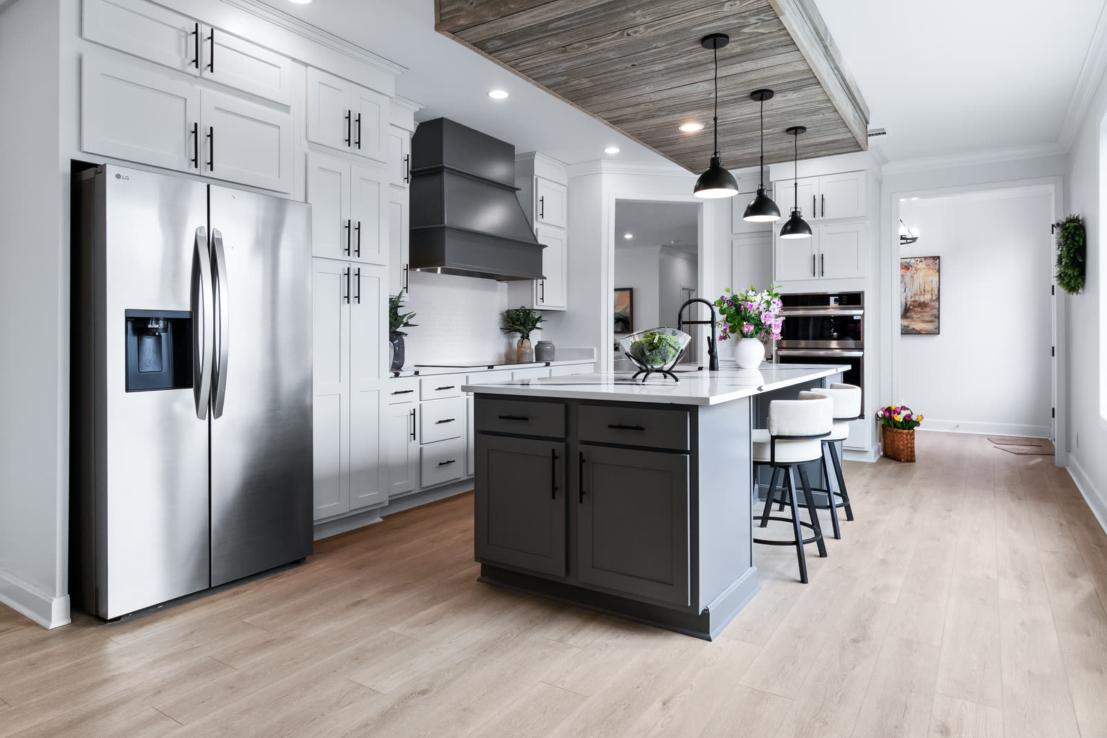 White kitchen with a gray island and stainless refrigerator