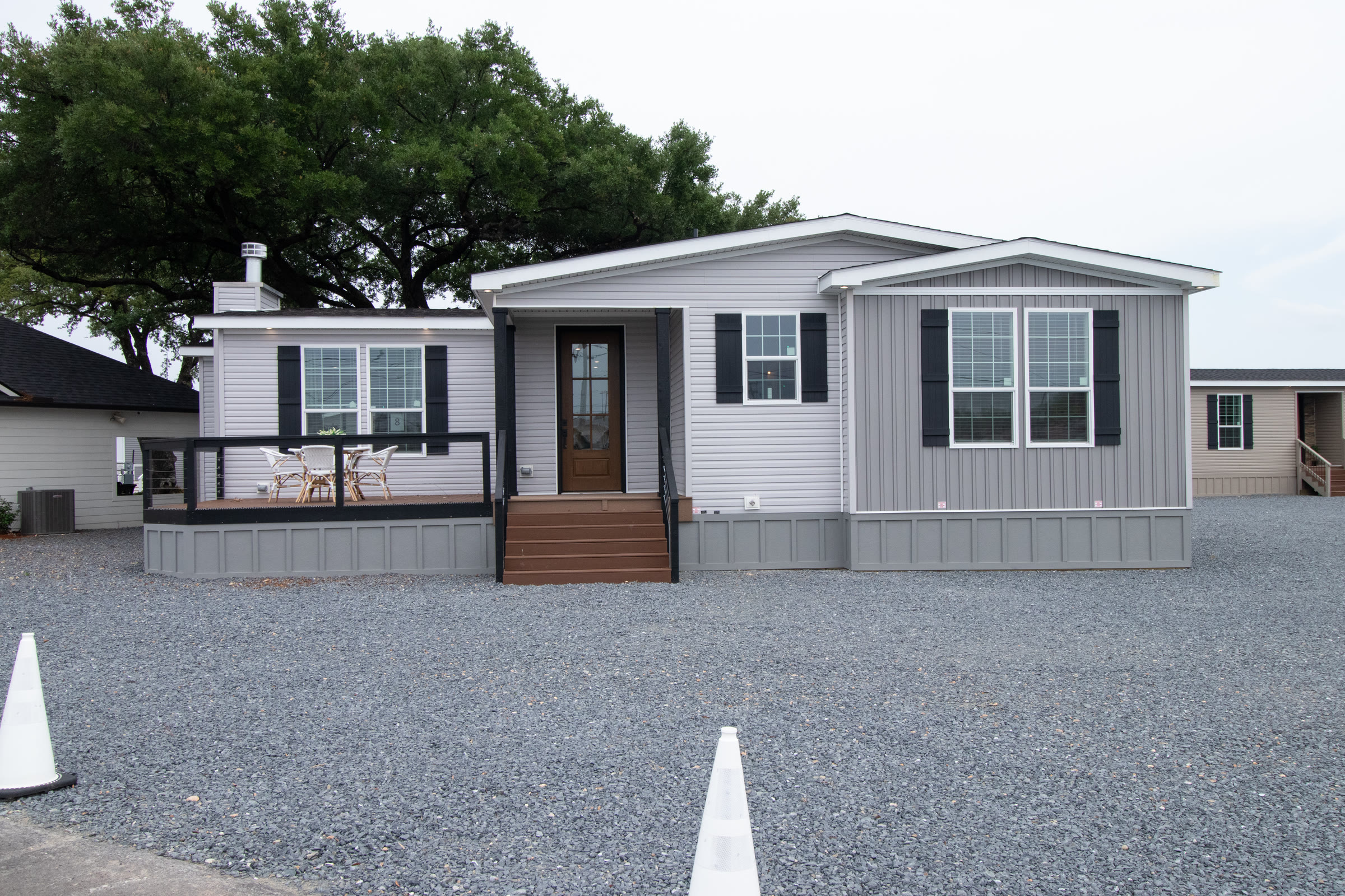 Gray manufactured home with a covered front porch and black shutters